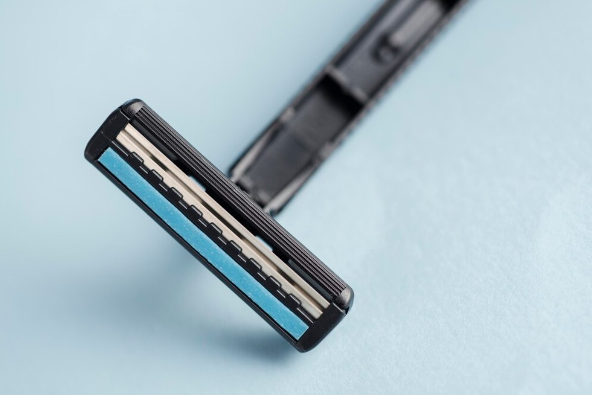 Close-up of a black razor with a blue rubber strip, set against a light blue background, emphasizing its sleek design.