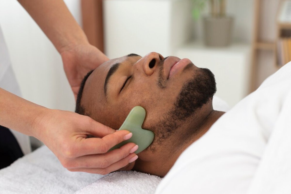 A person receives a soothing massage with a jade tool on their neck while resting on a towel in a tranquil spa setting.