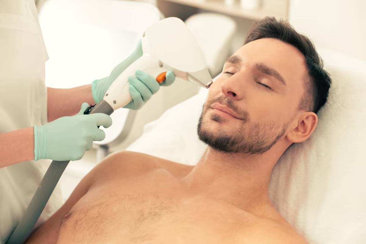 A healthcare professional using a laser treatment device on a male patient's face, while he relaxes on a treatment bed.
