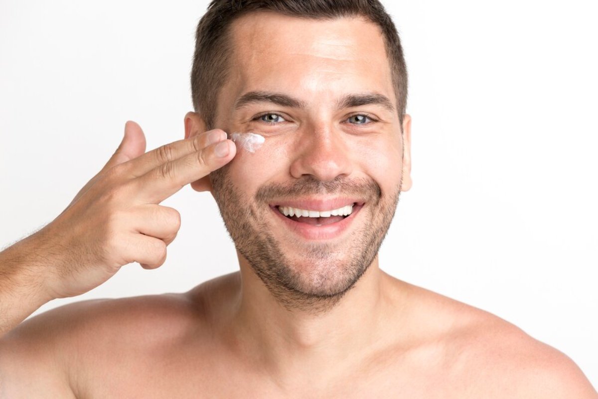 A shirtless man poses with a finger gun gesture near his head, against a plain white background.